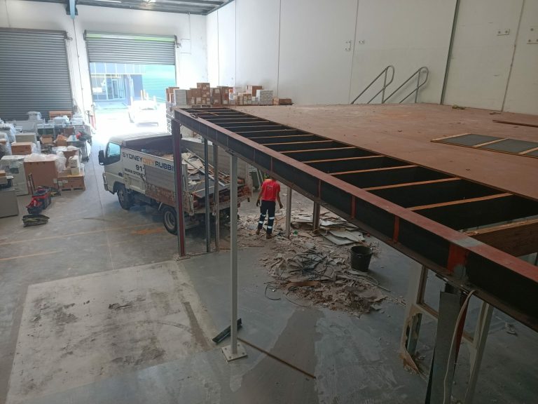 A rubbish removal team dismantles a warehouse mezzanine floor