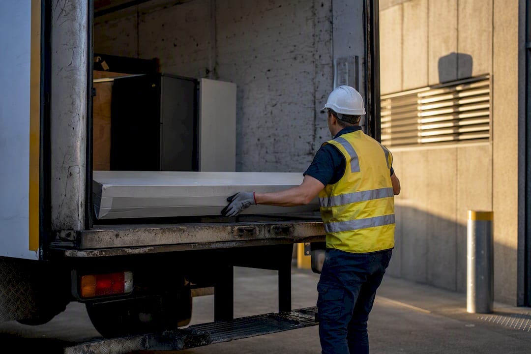 Crew member loading fluorescent tubes onto rubbish truck