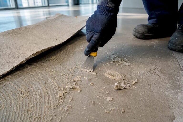 Worker scraping vinyl glue from concrete