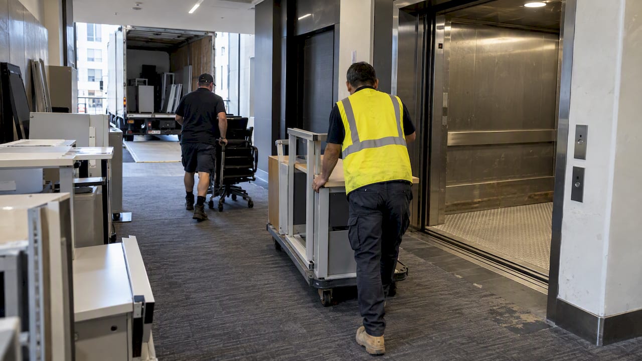 Commercial crew loading office furniture into freight lift