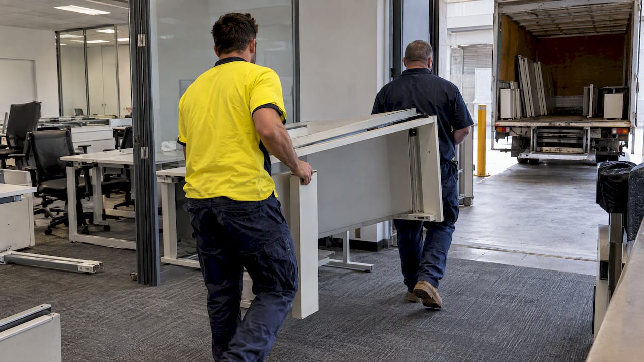 Crew moving dismantled office furniture for removal