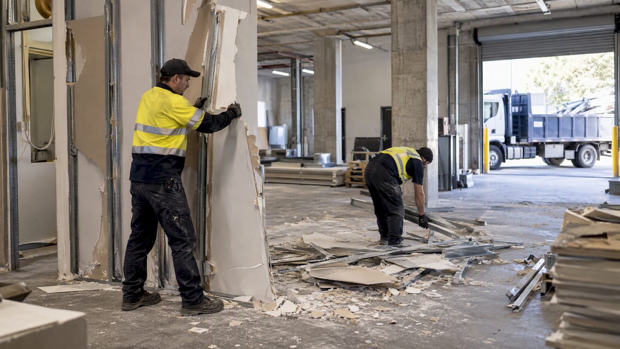 Crew removing office partition near commercial truck